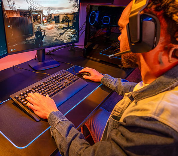 Close shot of a hand with long, glossy nails rests on a keyboard next to a Crucial T500 NVMe M.2 SSD on a pink surface.