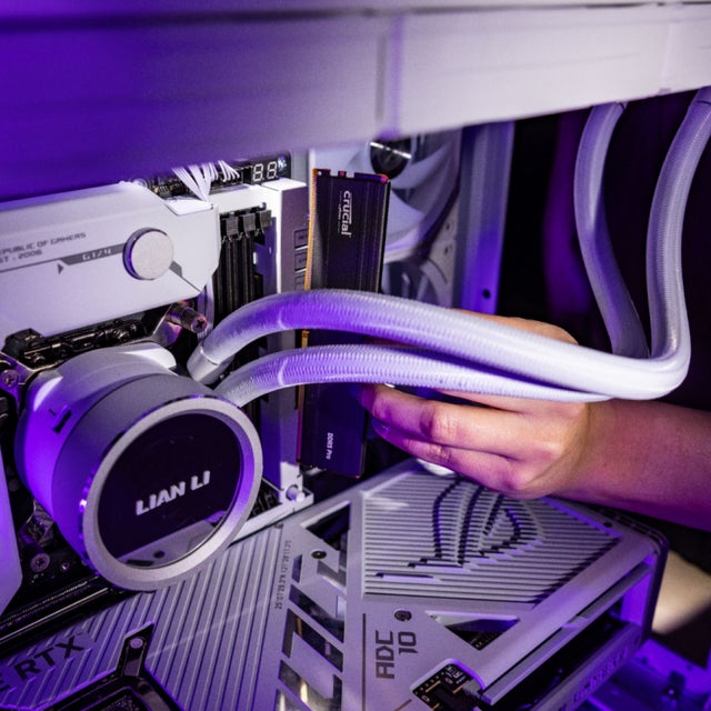 Close shot of a black Crucial DDR5 Pro DRAM being installed into a white gaming PC.