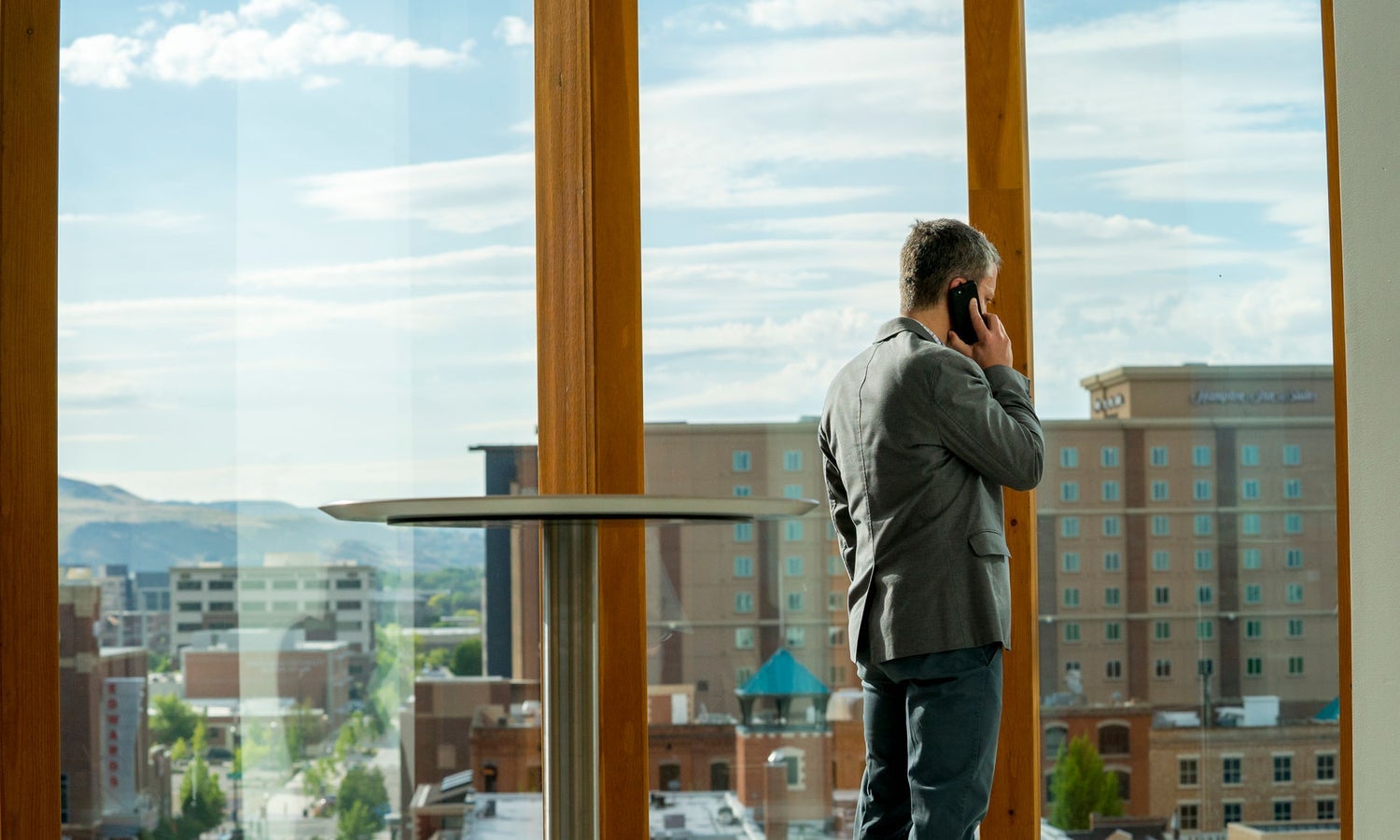 Man talking on phone with window view in background.
